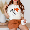 playera color hueso con diseƱo de fantasma con hacha y sombrero de bruja naranja